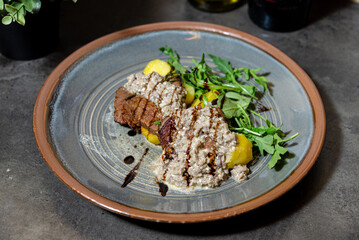 Beef medallions with creamy mushroom sauce. Plated dish featuring grilled beef medallions topped with creamy mushroom sauce, served with potatoes and fresh arugula greens.