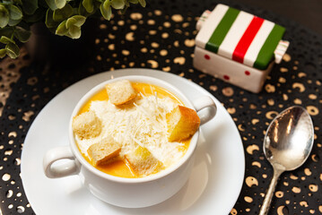 Creamy pumpkin soup with croutons and cheese. Delicious pumpkin soup served with shredded cheese and crispy croutons in a white cup, perfect for cozy autumn meals.