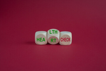 Wooden cubes with the expression 'heart check' and 'health check'. Beautiful pink background....