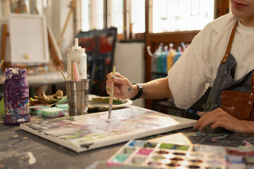 Fototapeta premium The artist paints with a brush. He creates modern masterpieces. Close-up.