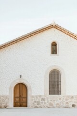 Rustic white chapel with wooden doors and stone accents under clear sky in a serene countryside setting during golden hour