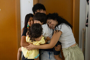 Diverse group of young friends hugging and laughing together indoors