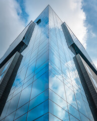 Obraz premium Modern glass skyscraper with blue sky reflection