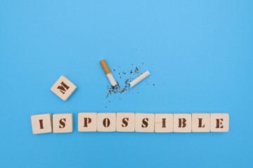 Broken cigarette with a positive message of handmade scrabble letters, encouraging people to quit smoking, on a blue background.