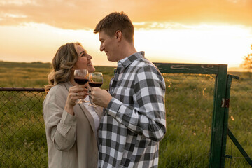 A couple shares an intimate moment gazing at each other while holding glasses, set against a...