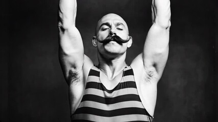 Vintage B&W footage: Circus strongman with handlebar mustache lifts heavy cast iron barbell. 19th-century style, striped singlet. Strength performance.