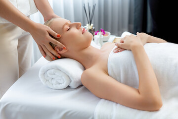 Naklejka premium Caucasian woman enjoying relaxing anti-stress head massage and pampering facial beauty skin recreation leisure in dayspa modern light ambient at luxury resort or hotel spa salon. Quiescent