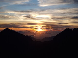 Spectacular sunset with backlit mountains (close-up view ). Maido, Reunion Island. Calm and dramatic atmosphere, for travel / nature / relaxation projects.