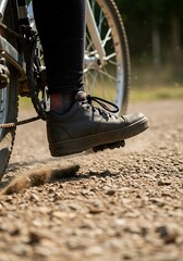 Close up of bicycle riding with black shoes on pedals on a gravel road