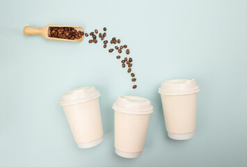 Flat lay of coffee beans pouring into a paper cup, blue backdrop used for food service or retail marketing content