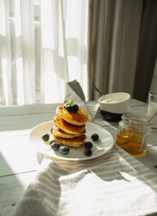 Cottage cheese pancakes with blueberries and sour cream on a white wooden table