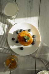 Cottage cheese pancakes with blueberries and sour cream on a white wooden table