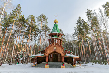 A small wooden church with golden domes and a cross on top of it in Yekaterenburg Russia
