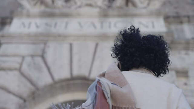 Woman tourist  at Vatican Museum gate with sculpture above entrance. Vatican City, papal enclave of Rome, Italy, slow motion isolated shot