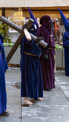 A solemn Semana Santa procession in Spain, featuring hooded penitents carrying ornate floats with religious statues, illuminated by candles and accompanied by haunting music.

