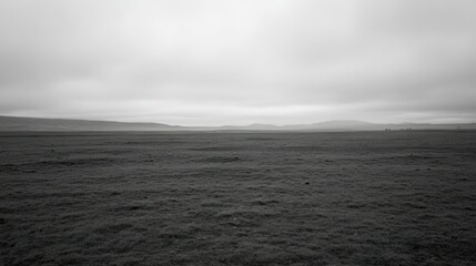 A monochrome image of a vast open grassy plain