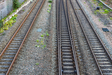 Fototapeta premium Parallel railway tracks running through gravel bed with surrounding green vegetation