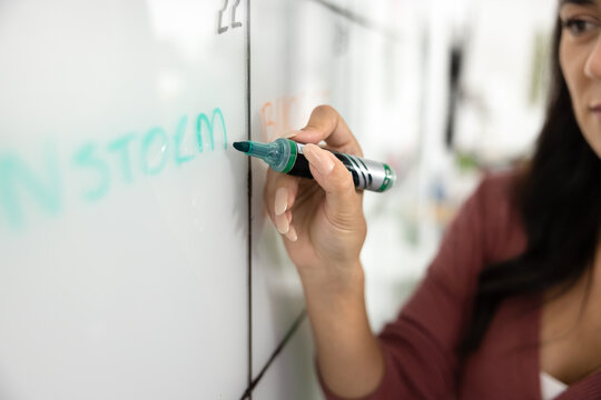 Planning brainstorming session for teamwork. Marker in young businesswoman hand writing schedule creating project timeline organizing time table visualizing work strategy on whiteboard wall. Close up