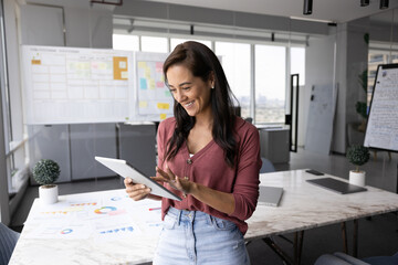 Smart and successful. Happy young woman business strategist project coordinator type on pad with...