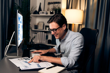 Smart businessman analyzing business paragraph dynamic database marketing analysis plan surrounded paper sheet and pc monitor report to compare with document data at home office at night. Pecuniary.