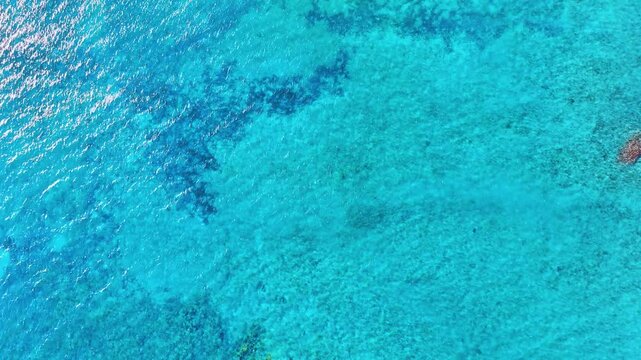 Turquoise ocean surface. Abstract background of sea water flow under sunlight. Sea from drone. Gentle ripples on water surface with light refraction. Sea background.