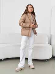Stylish model in modern studio poses in fashionable outerwear and relaxed attire