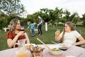 A cozy outdoor family dinner scene highlighting connections over meals and laughter in a lush green...