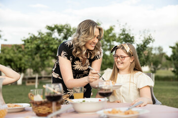 A caring moment captured as a mother serves pasta to her delighted daughter, showcasing love and family connection.