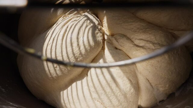 Bakery dough preparation close-up of a powerful mixer kneading fresh dough for bread, croissants, and other delicious pastries in a commercial kitchen. High quality 4k footage