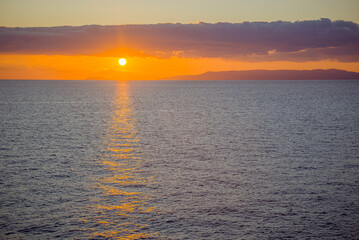 Obraz premium Kardamyli, Messenia, Mani, Greece: Sunset over the sea with distant land and clouds