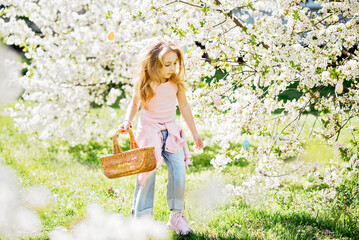 Easter egg hunt. Girl child Wearing Bunny Ears Running To Pick Up Egg In Garden. Easter tradition. Baby with basket full of colorful eggs.