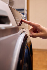 Individual Interacting with a Modern Washing Machines Control Panel for Efficient Laundry Tasks