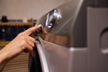 Individual Interacting with a Modern Washing Machines Control Panel for Efficient Laundry Tasks