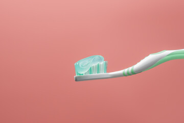A toothbrush with toothpaste on it. The toothpaste is green and white