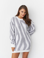 Stylish female model poses gracefully in a chic studio with a trendy sweater dress