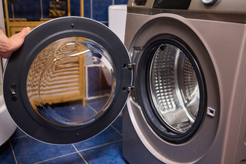 A contemporary modern washing machine with its door open, showcasing laundry inside