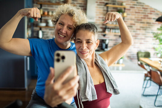 Senior women flexing muscles and taking selfie after home workout