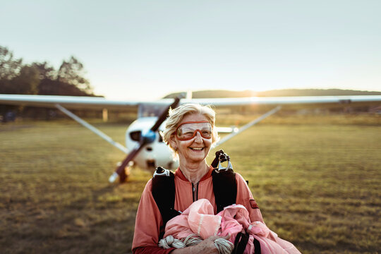 Happy senior woman after skydiving adventure at sunset airfield