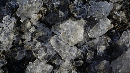 Close-up shot of small ice fragments on the shore, showcasing clear and detailed ice texture. Natural winter background.

