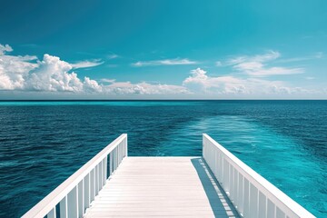 Pristine white wooden dock extends into turquoise ocean under a vibrant blue sky filled with fluffy clouds