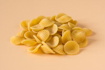 Side view of isolated a raw Italian durum wheat orecchiette pasta on a beige  background .
