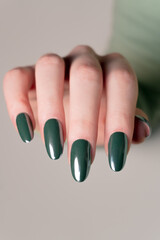 Elegant female hand with trendy dark green nails, a salon-perfect manicure that balances classic design with contemporary color.