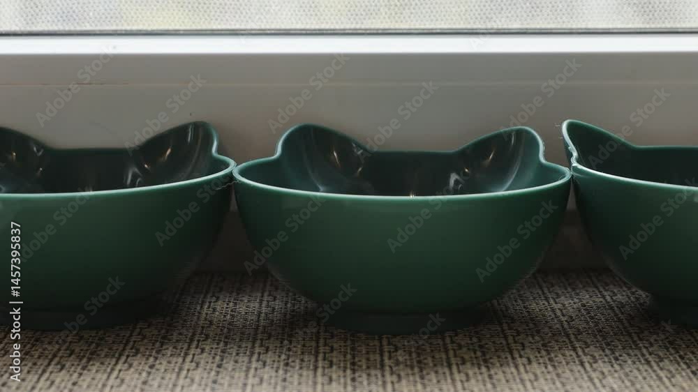 Poster three green bowls sit next to a window sill, perfect for storing small items or adding a pop of colo