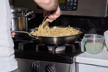 Cooking Spaghetti Pasta on Stove with Sauce Preparation
