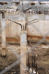 Abandoned construction site with exposed rebar and concrete columns in urban setting