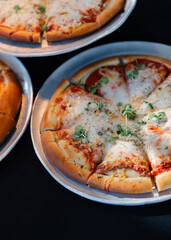 Freshly baked pizza served on metallic trays at a casual dining setting during the evening