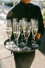 Waiter serving champagne in elegant glasses at a stylish outdoor event during sunset