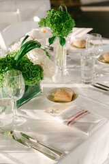 Elegant dining table setup with flowers and bread rolls for a special event in a bright venue
