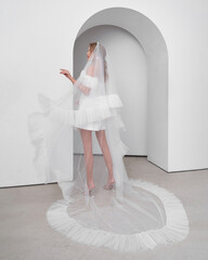 Blonde woman in unique wedding dress posing gracefully in elegant bright interior