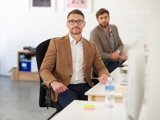 Businessman, glasses and portrait on desk, serious and coworking of colleagues, computer and together. Face, working and entrepreneur in company, journalist and confidence in startup and creative